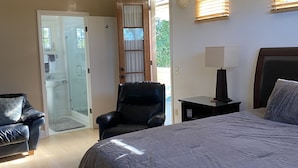 A bedroom with a large bed, a chair, a desk with a lamp, and a door leading to a bathroom. - Coastal Studio Retreat!! WALK TO SURF & SAND or 1 MIN DRIVE!!! GREAT LOCATION!!! (Carlsbad)