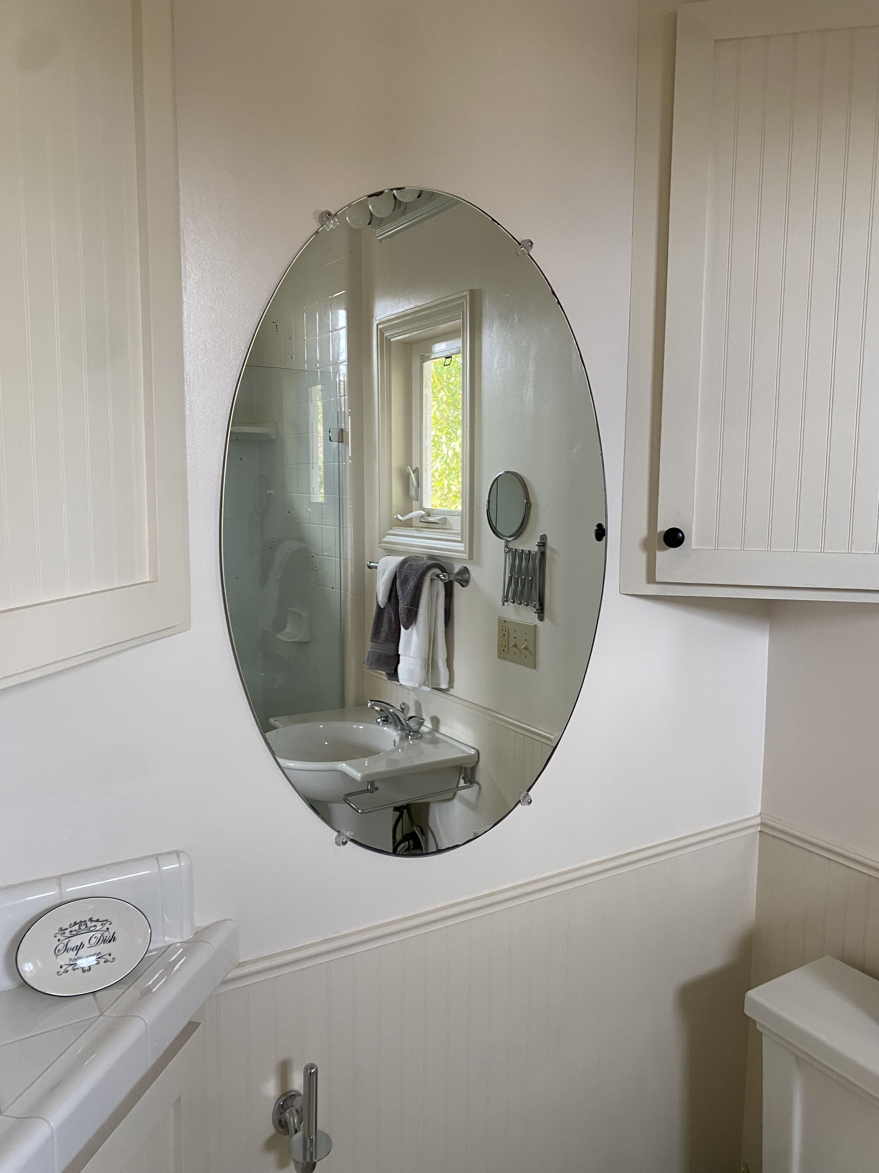 Une salle de bain avec un miroir rond, un lavabo et des toilettes.