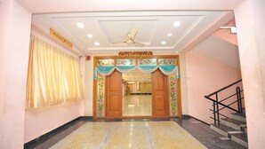 L’entrée d’un hôtel, avec une enseigne indiquant « Gehranjali », un ventilateur de plafond et un escalier sur la droite.
