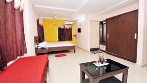 Une chambre d’hôtel avec un lit, une couvre-lit rouge, une table basse en verre, une armoire et un climatiseur fixé au mur.