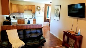A living room with a black leather couch, a TV, and a wooden coffee table. - The Cottage on Campbell- In town studio with a view!  (Mariposa)