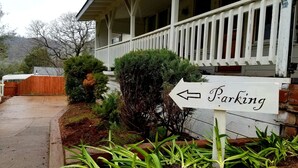 A house with a porch and a sign indicating a parking area. - The Cottage on Campbell- In town studio with a view!  (Mariposa)