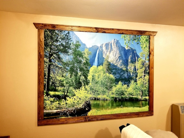 A room with a large framed landscape painting of a mountainous area with trees and a lake. - The Cottage on Campbell- In town studio with a view! (Mariposa)