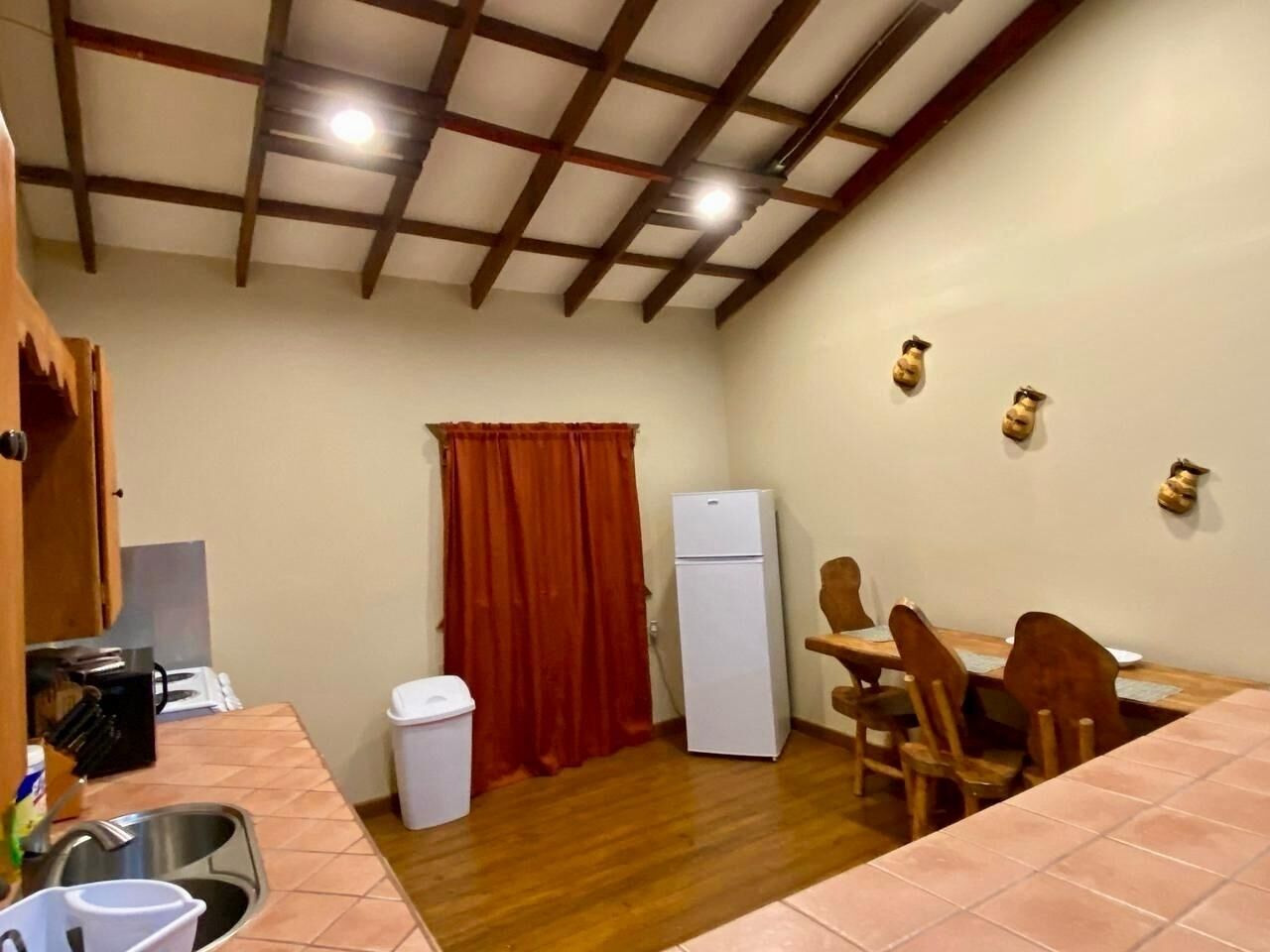 A compact kitchen with a sink, a refrigerator, and a dining area with chairs and a table.