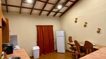 A compact kitchen with a sink, a refrigerator, and a dining area with chairs and a table.