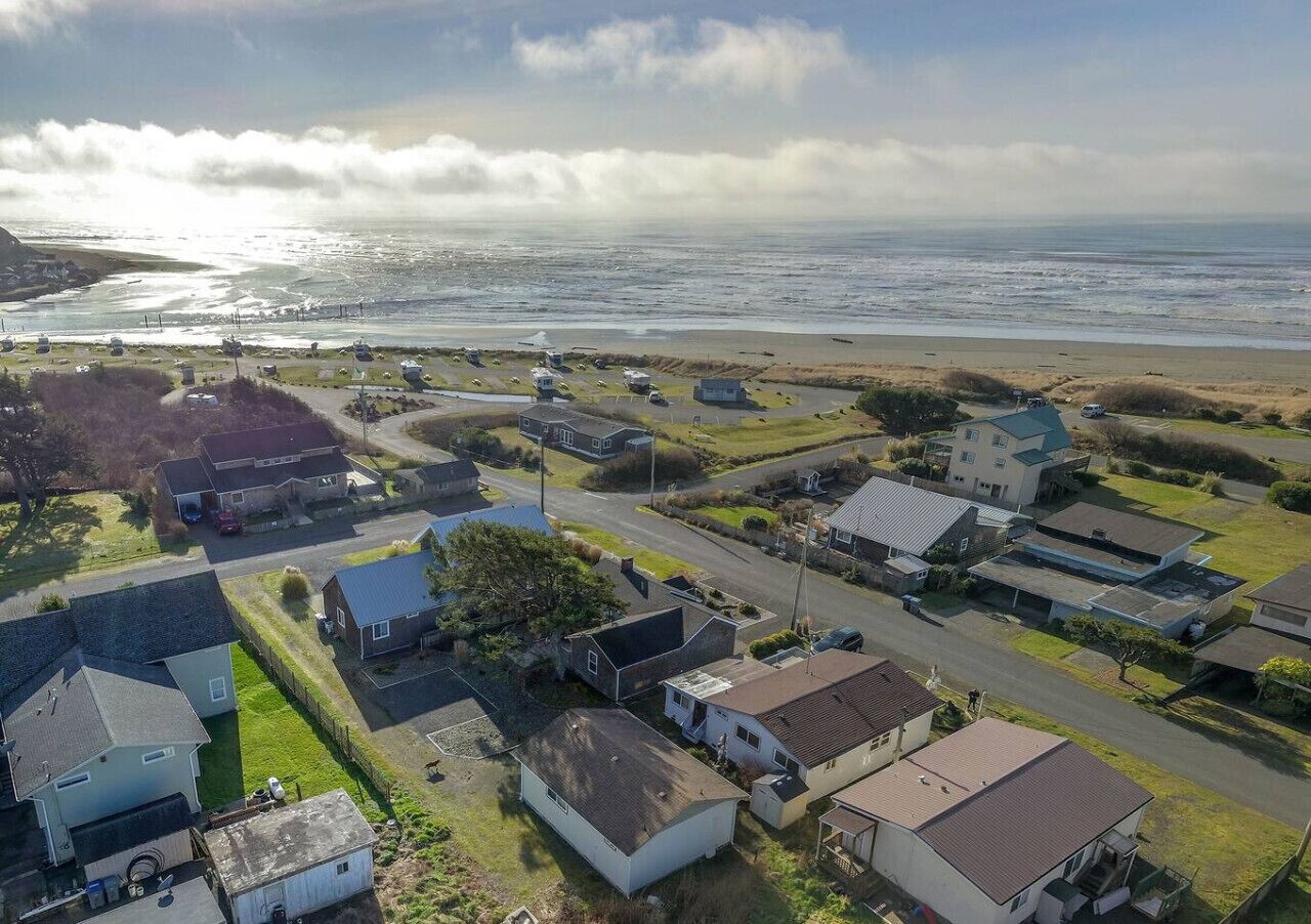 Vista aérea de una zona residencial costera con casas, una carretera y una playa.