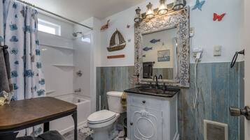 A bathroom with a bathtub, toilet, vanity, and a shower curtain.