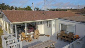 Une maison de plain-pied dotée d’un porche couvert, d’une terrasse en bois et d’une grande porte-fenêtre coulissante donnant sur un espace patio.