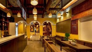 Un restaurant chaleureux avec des bancs et des tables en bois, un coin bar et un escalier menant à un étage supérieur.