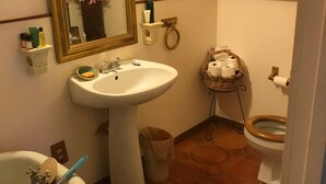 A bathroom with a pedestal sink, a bathtub, a toilet, and a mirror. - The Zen-ter BNB Suite #1 in the Heart of Carrollton Georgia (Carrollton)