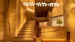 Een modern interieur met een marmeren trap, een receptiebalie en een kroonluchter.