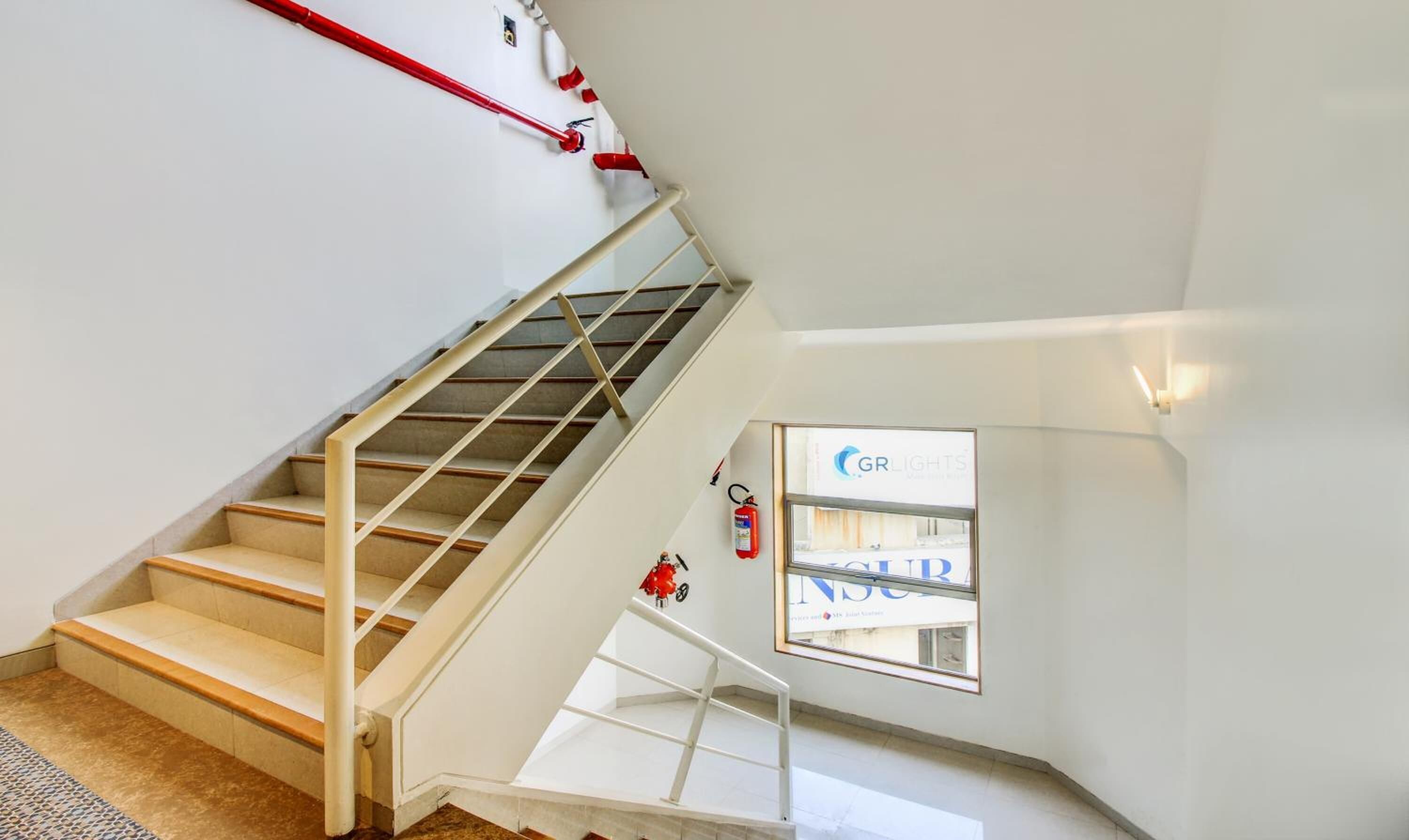 Eine Treppe mit Handlauf, einem Feuerlöscher und einem Fenster mit einem Schild.