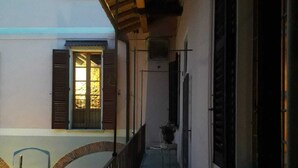 A narrow corridor with a wooden railing, a small table with a chair, and a potted plant. - Secret Garden Art Museum (Arona)