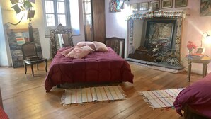 A room with a bed, wooden flooring, a fireplace, and a chair. - Secret Garden Art Museum (Arona)