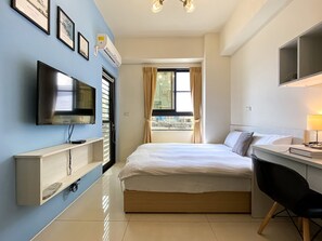 A hotel room with a bed, a desk, a chair, a TV, and a window with curtains. - Adagio Hostel (Taichung)