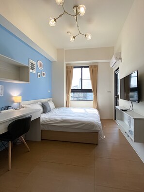 A modern hotel room with a bed, desk, chair, and a TV. - Adagio Hostel (Taichung)