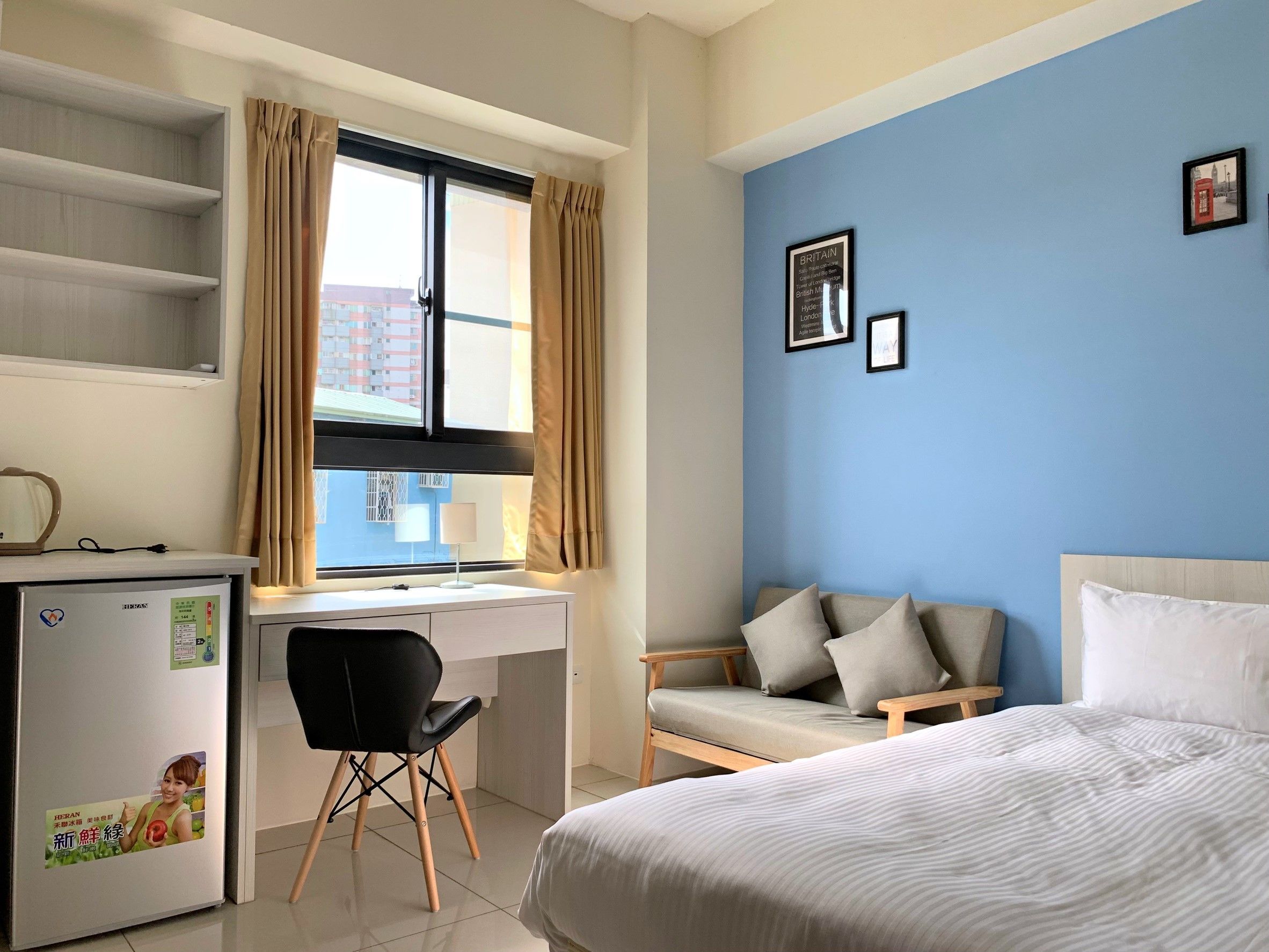 A bedroom with a bed, a desk, a chair, and a window with curtains.