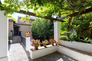 A courtyard with a tiled floor, potted plants, and a pergola structure.
