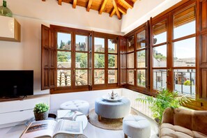 A cozy living room with a large window, a television, and comfortable seating.