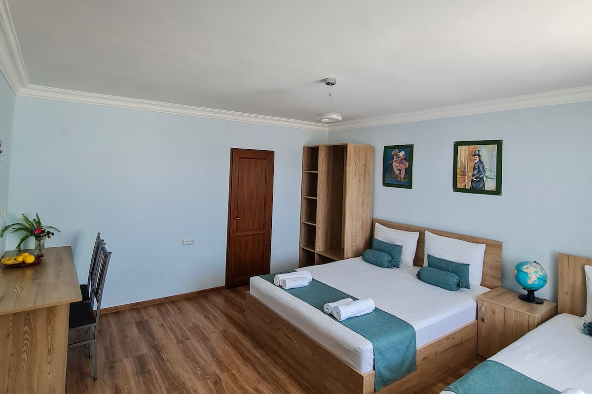 A bedroom with two beds, a wooden desk, and a globe on a nightstand.