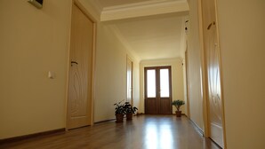 A hallway with wooden floors, cream walls, and a door at the end. - Seva Guesthouse in Byurakan (Byurakan)