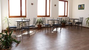A spacious dining area with multiple tables and chairs, large windows, and potted plants. - Seva Guesthouse in Byurakan (Byurakan)