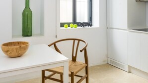Cuina moderna amb armaris blancs, una finestra amb vistes i zona de menjador amb taula i cadires.