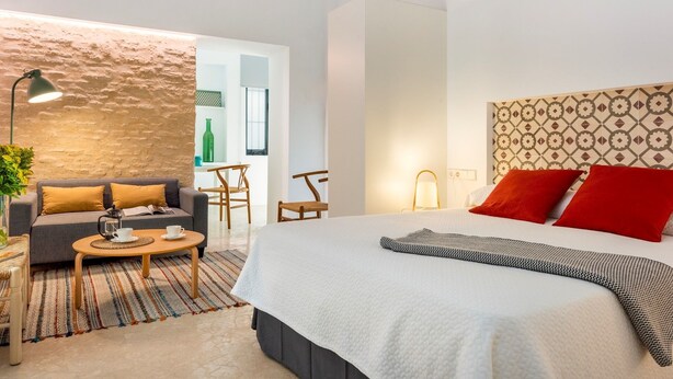 Habitació d'hotel moderna amb un llit gran, un sofà, una taula petita i un escriptori.