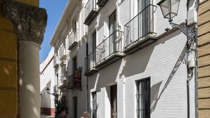 A narrow cobblestone street flanked by historic buildings with balconies and traditional street lamps. - Genteel Home Santa Teresa VI (Sevilla)