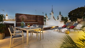 A rooftop terrace with a dining table and chairs, a lounge area with sun loungers, and a decorative fence. - Genteel Home Santa Teresa VI (Sevilla)