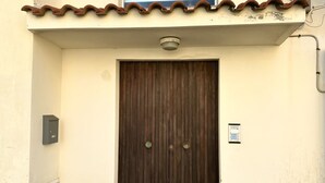Una porta de fusta tancada amb un mànec metàl·lic, una caixa de seguretat i un petit cartell a la paret.