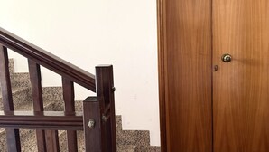 Una escala de fusta amb barana que condueix a una porta amb mànec metàl·lic.