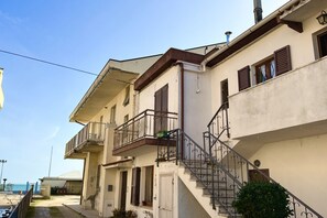 A row of two-story buildings with balconies, a staircase, and a clear sky. - M223 - Marcelli, three-room apartment in the center and facing the sea (Marcelli)