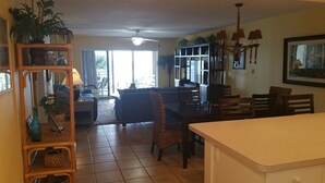 A spacious living area with a sofa, dining table, chairs, and a kitchen counter. - Enjoy your beach holiday in this updated oceanfront two bedroom, two bath condo. (New Smyrna Beach)