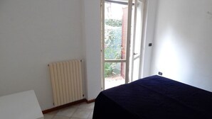 Et værelse med en seng, en radiator og en dør til et udendørs område.