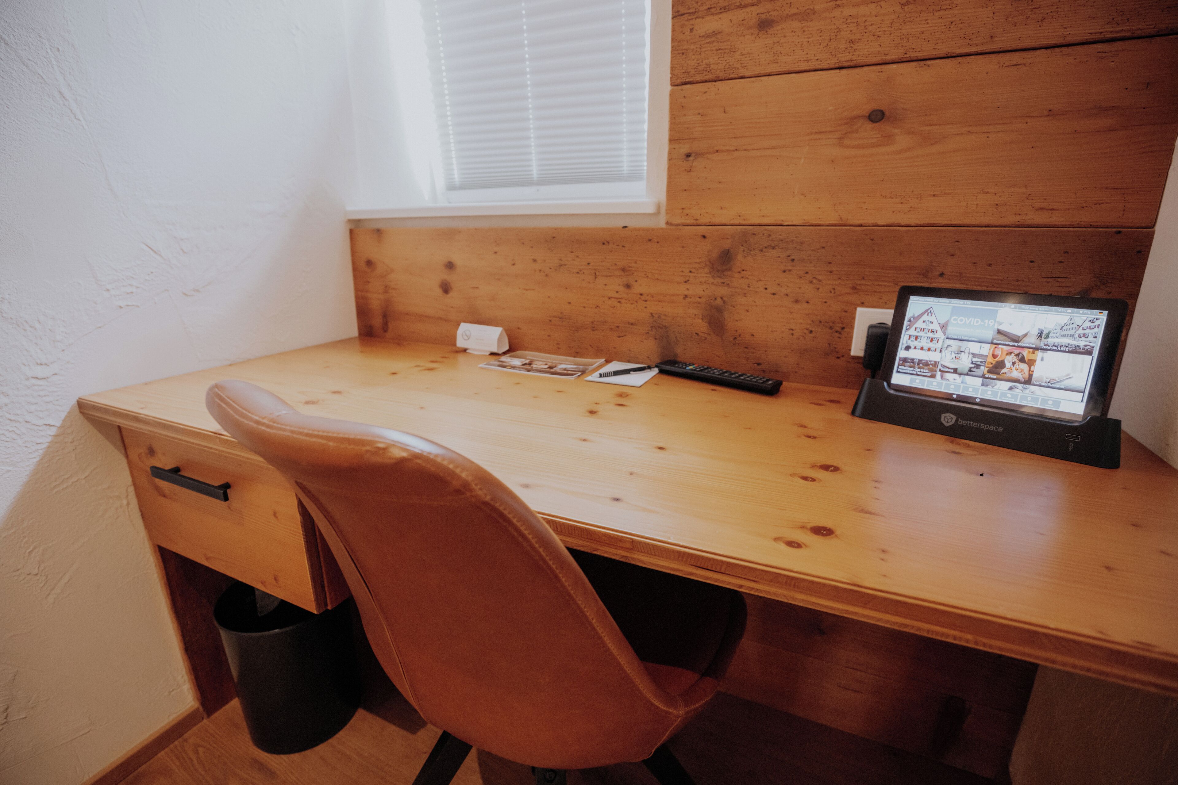 A wooden desk with a laptop, a remote control, and a small box.