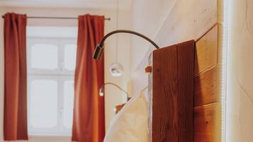 Een slaapkamer met een houten hoofdbord, een nachtkastje, een lamp en een raam met gordijnen.