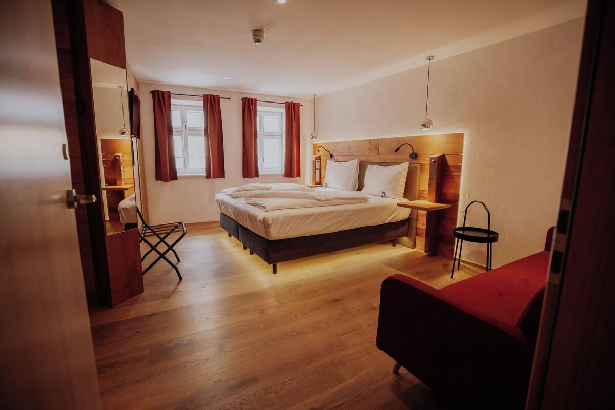A bedroom with a bed, a chair, a nightstand, and a window with curtains.