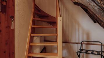 Una escalera de madera en una habitación con techo inclinado y vigas de madera.