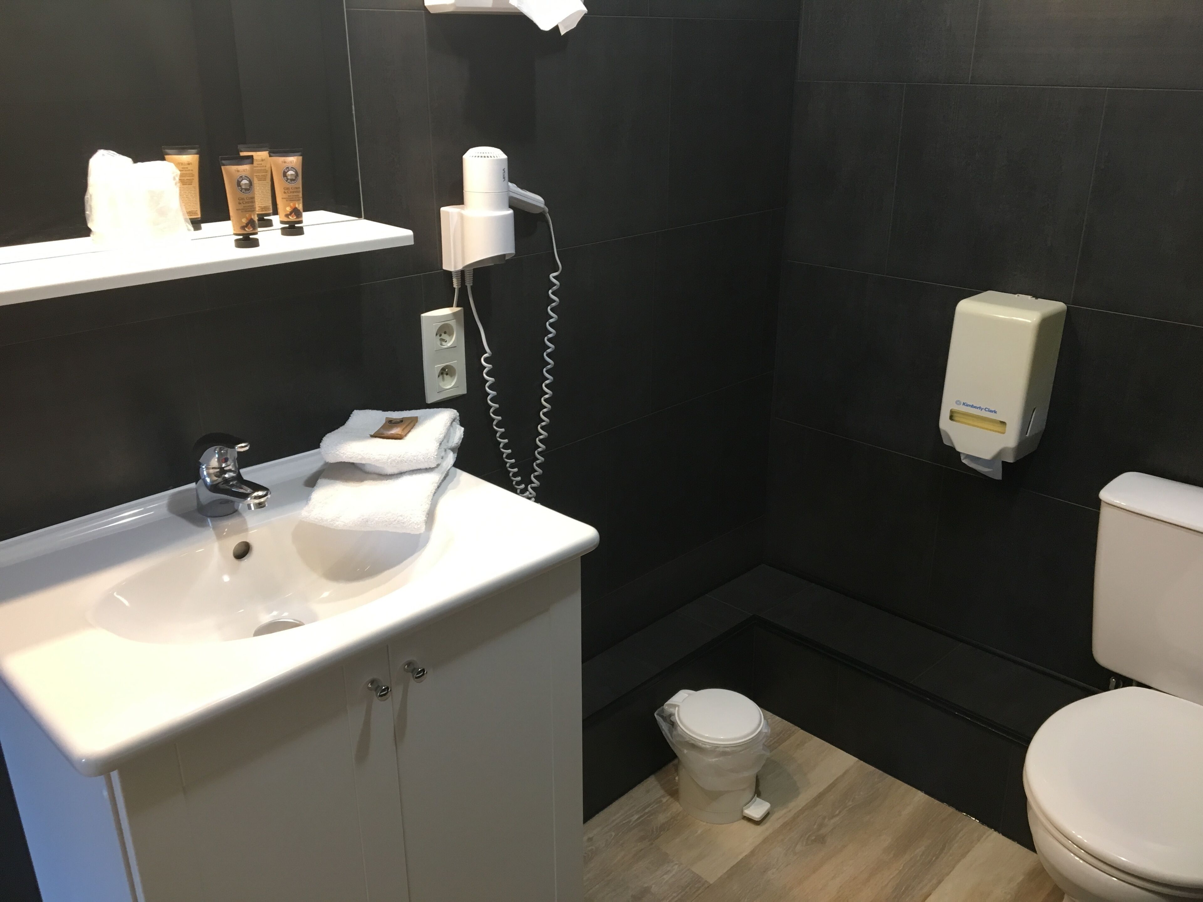 Un baño moderno con un lavabo blanco, inodoro y zona de ducha.
