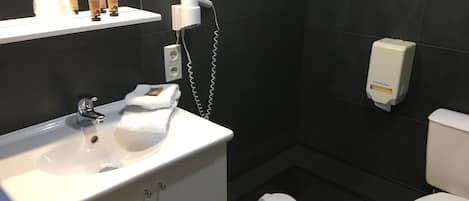 Un baño moderno con un lavabo blanco, inodoro y zona de ducha.