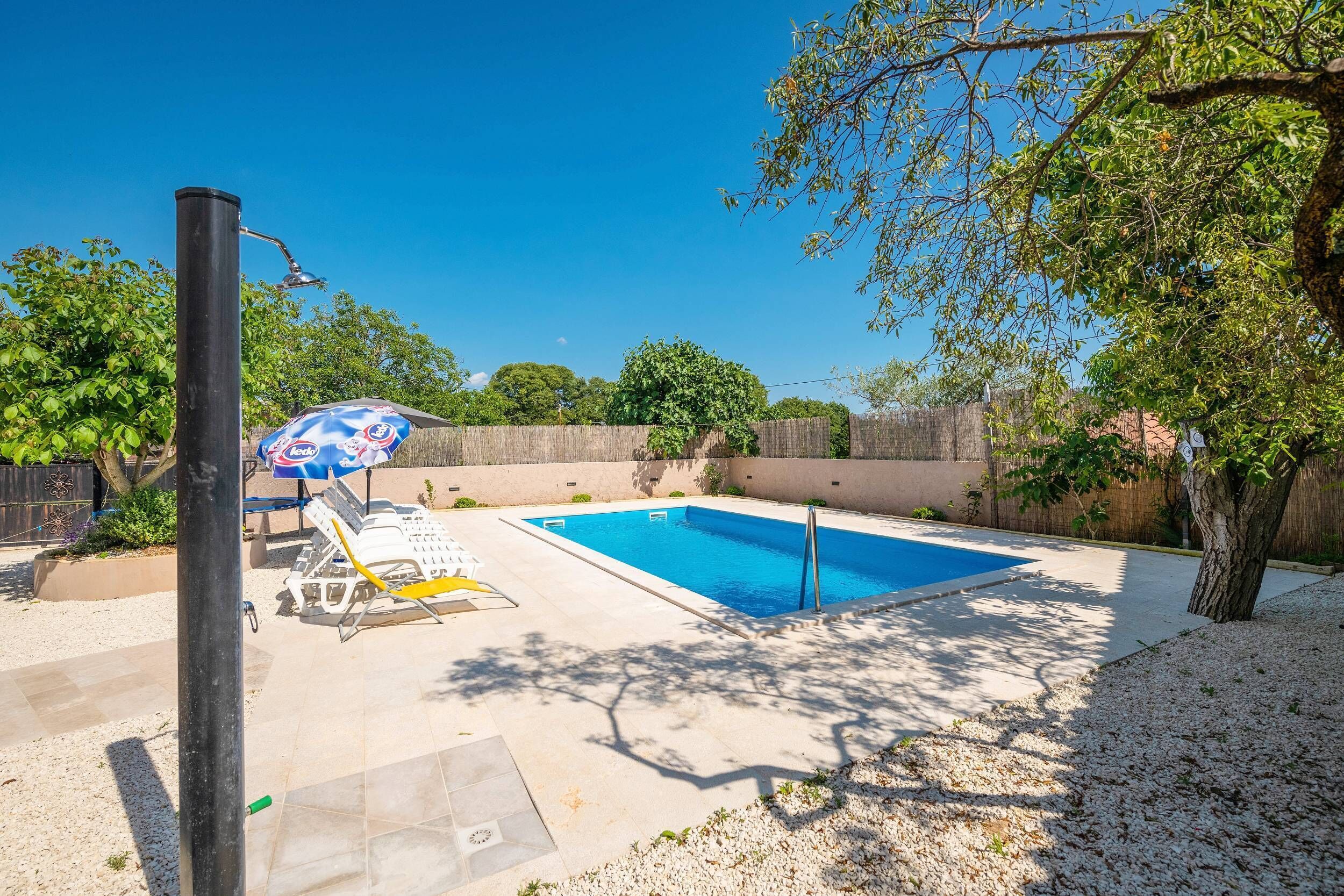 A backyard with a swimming pool, a covered seating area, and a pergola.