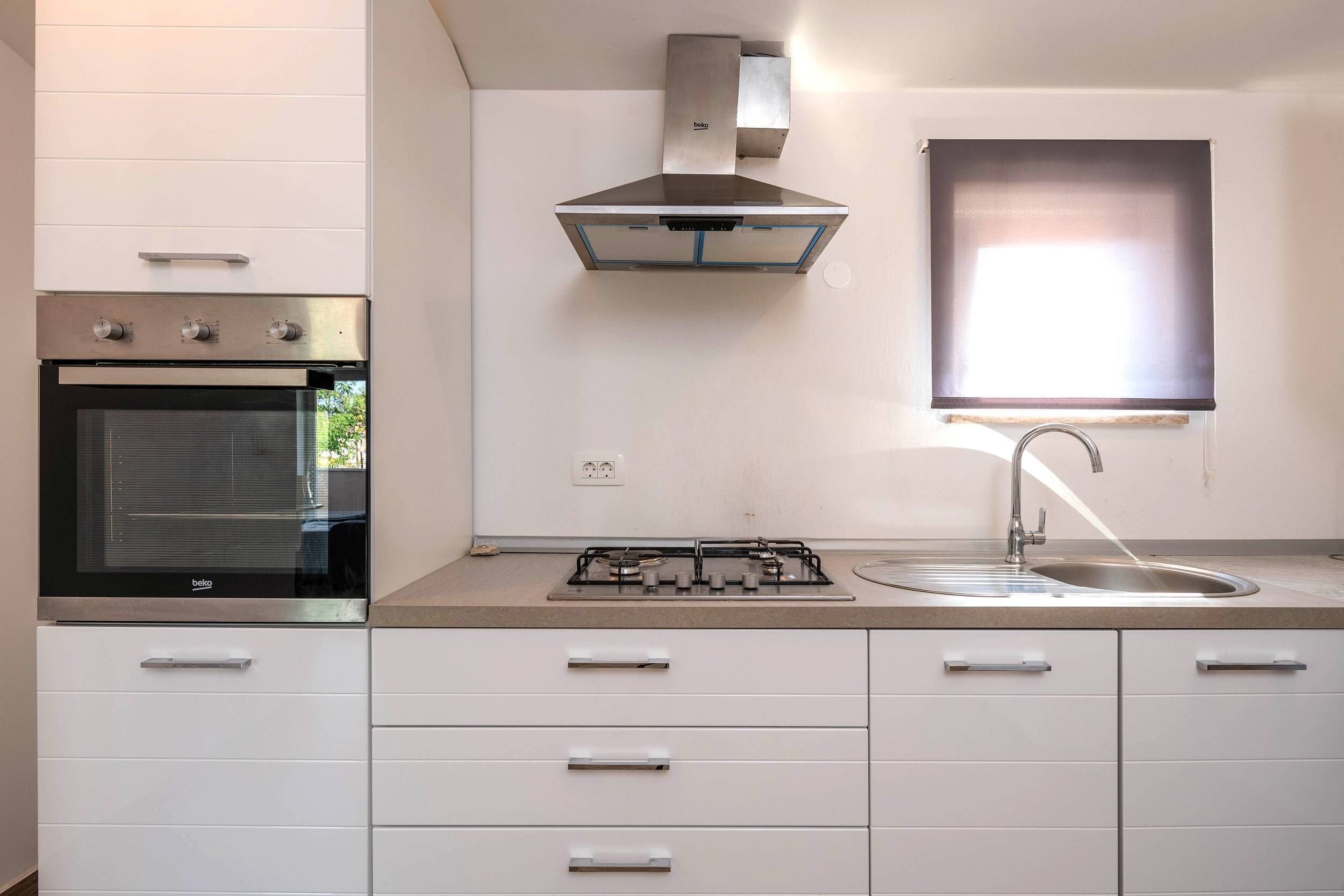 Une cuisine moderne dotée d’un four encastré, d’une cuisinière à gaz et d’une hotte en acier inoxydable.