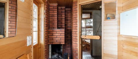 A wooden interior with a fireplace, wooden walls, and a tiled floor.