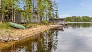 A lakeside cabin with a dock extending into the water, surrounded by trees and a sandy shoreline. - Wuorilahti by Interhome (Savonlinna)