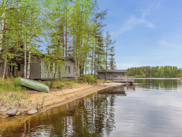 A lakeside cabin with a dock, surrounded by trees and a calm water body.