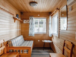 A cabin interior with a wooden bench, a small table, and a window with curtains. - Wuorilahti by Interhome (Savonlinna)