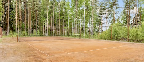A tennis court surrounded by tall trees.