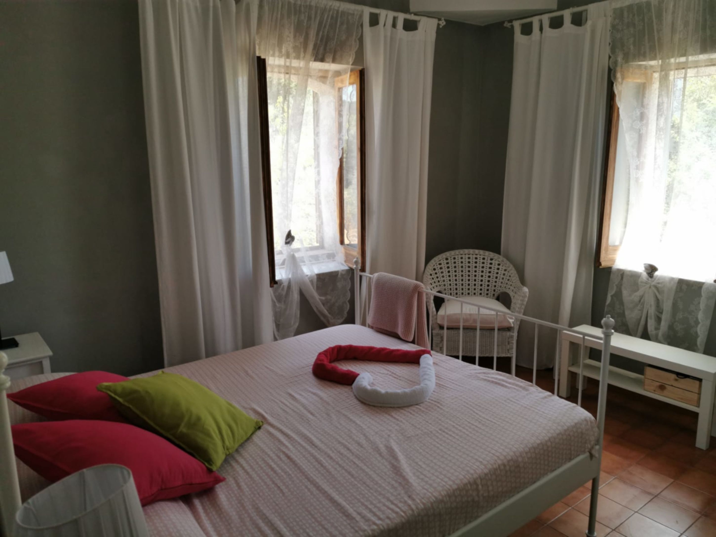 A bedroom with a bed, pillows, a chair, and a window with curtains.