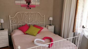 A bedroom with a bed, pillows, a nightstand, a lamp, and a wall art piece.